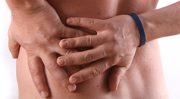 мужчина держится руками за поясницу слева от боли